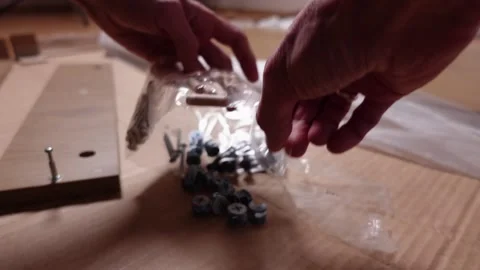 A young man twists a screw with a screwdriver into a board. Furniture assembly Stock Footage 240953959