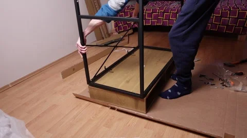A young man twists a screw with a screwdriver into a board. Furniture assembly Stock Footage 240954100