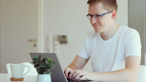 Young man tying text on laptop keyboard at home Stock Footage 156012048