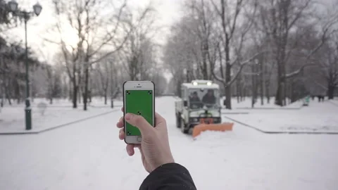 Young man types and slides on his smartphone in the winter park. Greenscreen Stock Footage 85595448