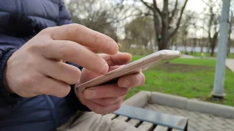 Young man types a text message or downloads an application for his smartphone. Stockbeeldmateriaal 188973123