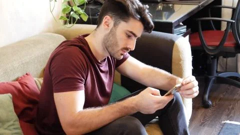 Young man typing and using cell phone Stock Photos