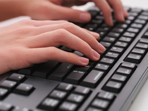 A young man typing on a black computer keyboard Stock Photos