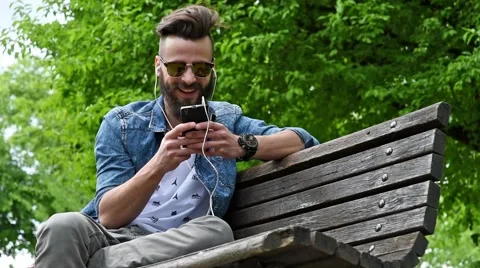Young man typing on cell phone at the park Stock Footage 62698710
