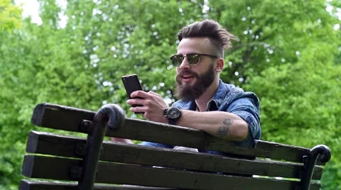 Young man typing on cell phone at the park Stock Footage 62698728