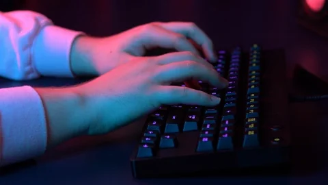 A young man is typing on a computer keyboard. Hands close up. Blue and red light Stock-Footage 125777524