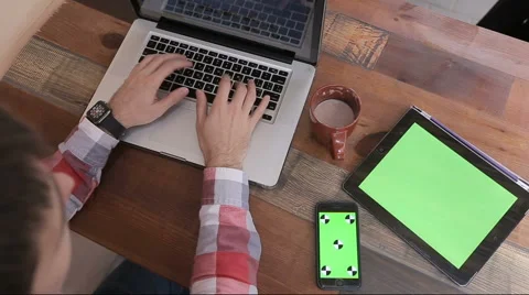 Young man typing on his laptop in cafe.Tablet with green screen. Stock Footage 62932271