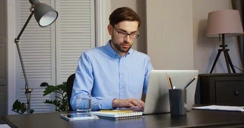 Young man typing on his laptop. Serious man working on laptop on office. Office Stock Footage 74497599