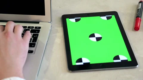 Young man typing on a laptop computer with a tablet with greenscreen Stock Footage 62802579