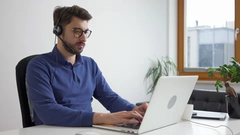 Young man typing on laptop working from home with headset Stock Footage 162467468