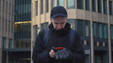 Young man typing message on screen smartphone on urban street in modern city Stock Footage 86489913