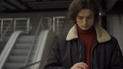 Young man typing on smartphone and rubbing chin Stock Footage 124704429
