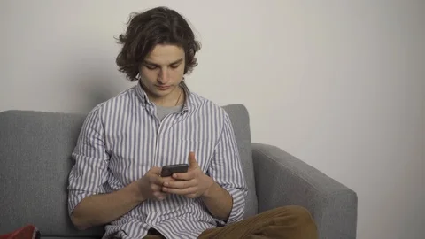 Young man typing on smartphone and looking at camera with smile 스톡 동영상 124704700