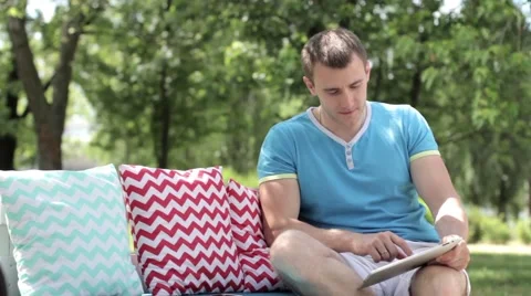 Young man typing on the tablet in nature Stock-Footage 65156287