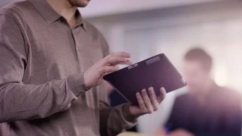 Young man is typing on a tablet in office while businessgroup Stock Footage 72338549