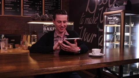 Young man typing on the tablet pc. Background of inscriptions and showcases. Vidéo 49766435