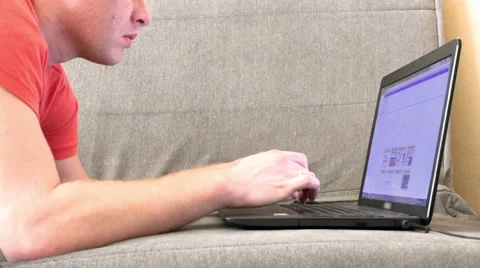 Young man typing text on a laptop while sitting on the couch Stock Footage 47429724