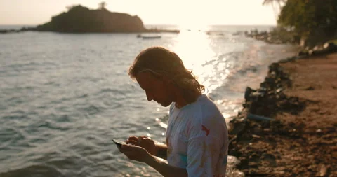 Young man typing text on a smartphone near the beach Stock Footage 105732154
