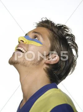 Young man with Ukrainian flag painted on face, looking up, close-up Stock Photos