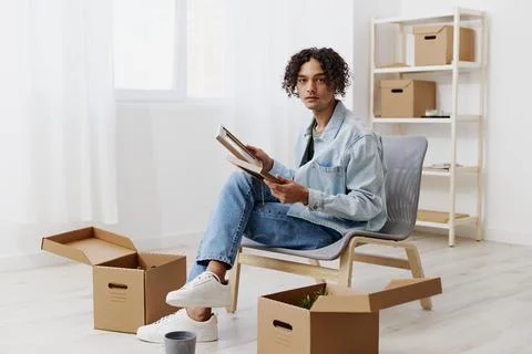 A young man unpacking things from boxes in the room sorting things out Stock Photos