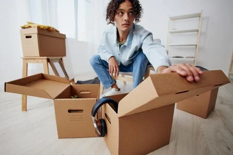 A young man unpacking things from boxes in the room sorting things out Stock Photos