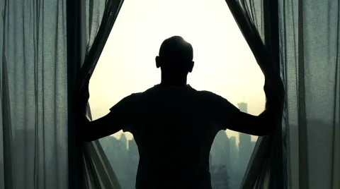 Young man unveil curtains and admire cityscape view, slow motion Stock Footage