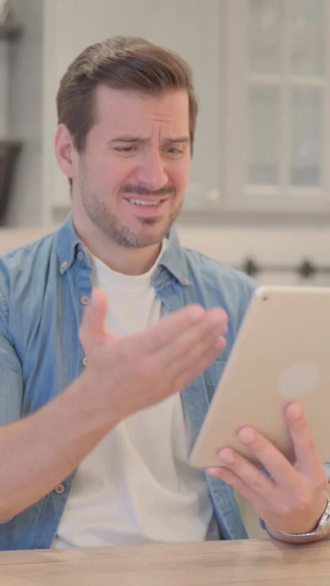 Young Man Upset by Loss on Tablet, vertical video Vídeos de archivo 328566009