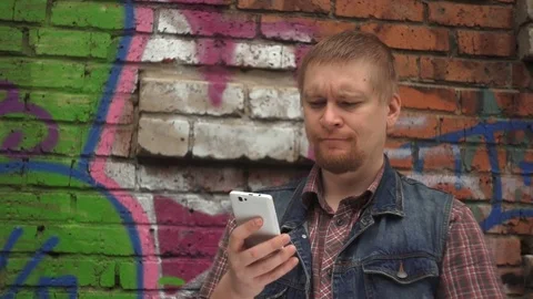 Young man use cellphone and near of a wall painted with graffiti Stock Footage 77636987