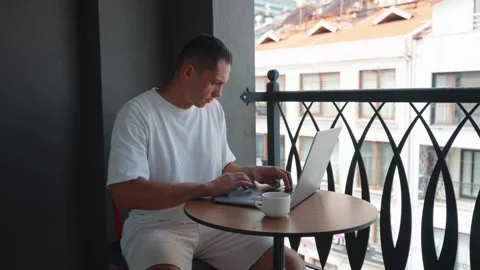 Young Man Use Laptop Computer On Terrace Drinking Coffe. Caucasian Man Typing Video stock 278618378