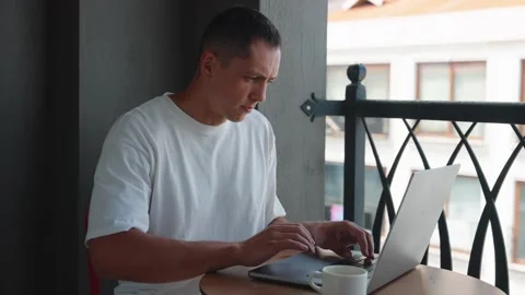 Young Man Use Laptop Computer On Terrace Drinking Coffe. Caucasian Man Typing Stock Footage 285601230