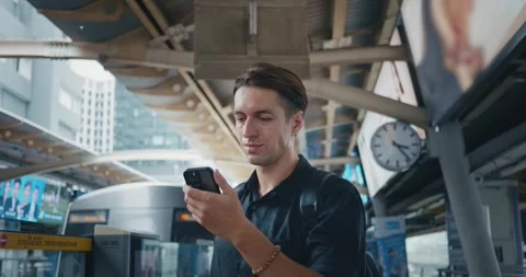 Young man use smartphone in subway station while waiting for arrival upcoming Stock Footage 250193873