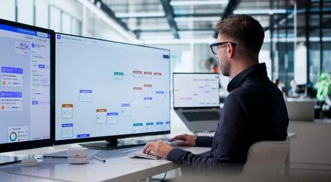 Young Man Uses Computer Software To Improve Business Workflow Automation. Stock Photos