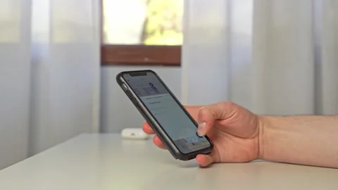 A young man uses his iPhone with a protective black bumper to thumb type a Stock Footage 213445050