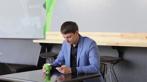 A young man uses his mobile device in a cafe Stock Footage 73965537