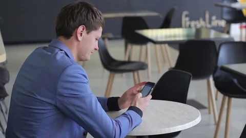 A young man uses his mobile device in a cafe Stock Footage 73966116