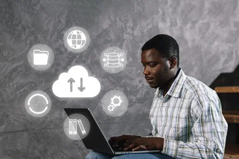 Young man uses laptop for data management and cloud services in a tech space 写真素材