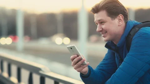 A young man uses a mobile phone at sunset in the city. Stock Footage 88298909