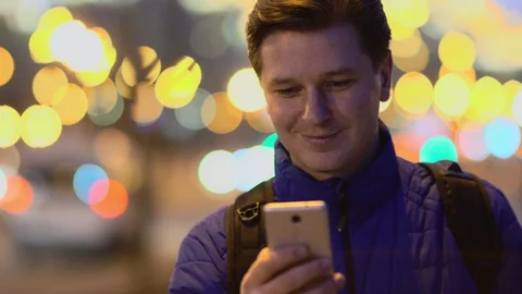 A young man uses a mobile phone at sunset in the city. Stock Footage 88300077
