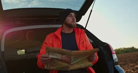 A young man uses an old map to search for treasures with a metal detector. Stock Footage 272318945