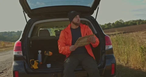 A young man uses an old map to search for treasures with a metal detector. Stock Footage 272319628
