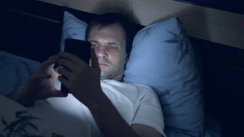 A young man uses a smartphone in bed at night. insomnia Stock-Footage 128501840