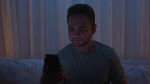 A young man uses a smartphone in bed at night Stock Footage 318464256