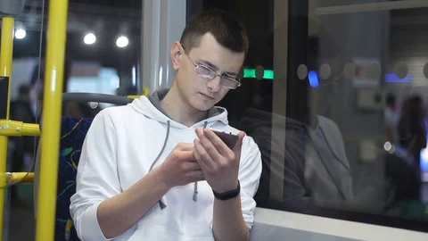 Young man uses a smartphone gadget on a public bus Stock Footage 87136335