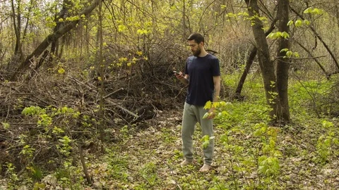 Young man uses a smartphone in a spring forest Vídeo Stock 80654204