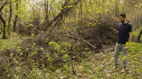 Young man uses a smartphone in a spring forest Vídeos de archivo 80654384