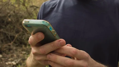 Young man uses a smartphone in a spring forest 動画素材 80696986