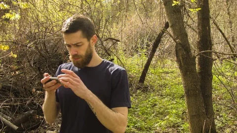 Young man uses a smartphone in a spring forest 스톡 동영상 80697573