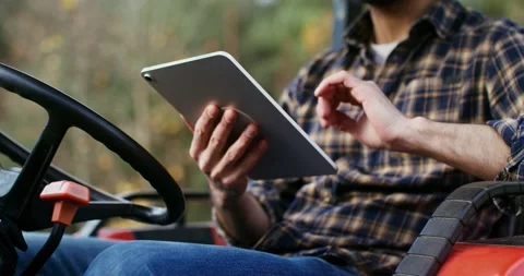 A young man uses a tablet while sitting in a standing agricultural machine Stock Footage 166861924