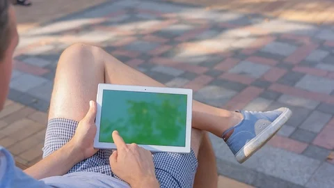 Young man uses TabletPC with green screen sitting on the bench in city park 1 Stock Footage 116409214