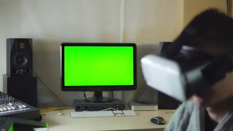 The young man uses the VR helmet on a green background screen Stock Footage 72445902